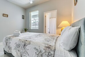 A bedroom with a bed, a bedside lamp, a window, and a door. - Spacious Kissimmee Villa w/ Private Pool & Hot Tub (Kissimmee)