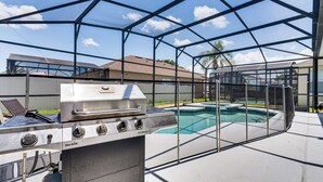 Un barbecue à gaz, une piscine et un patio couvert.