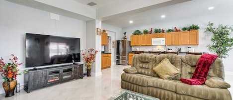 A modern living room with a flat-screen TV, a sofa, and a glass coffee table.