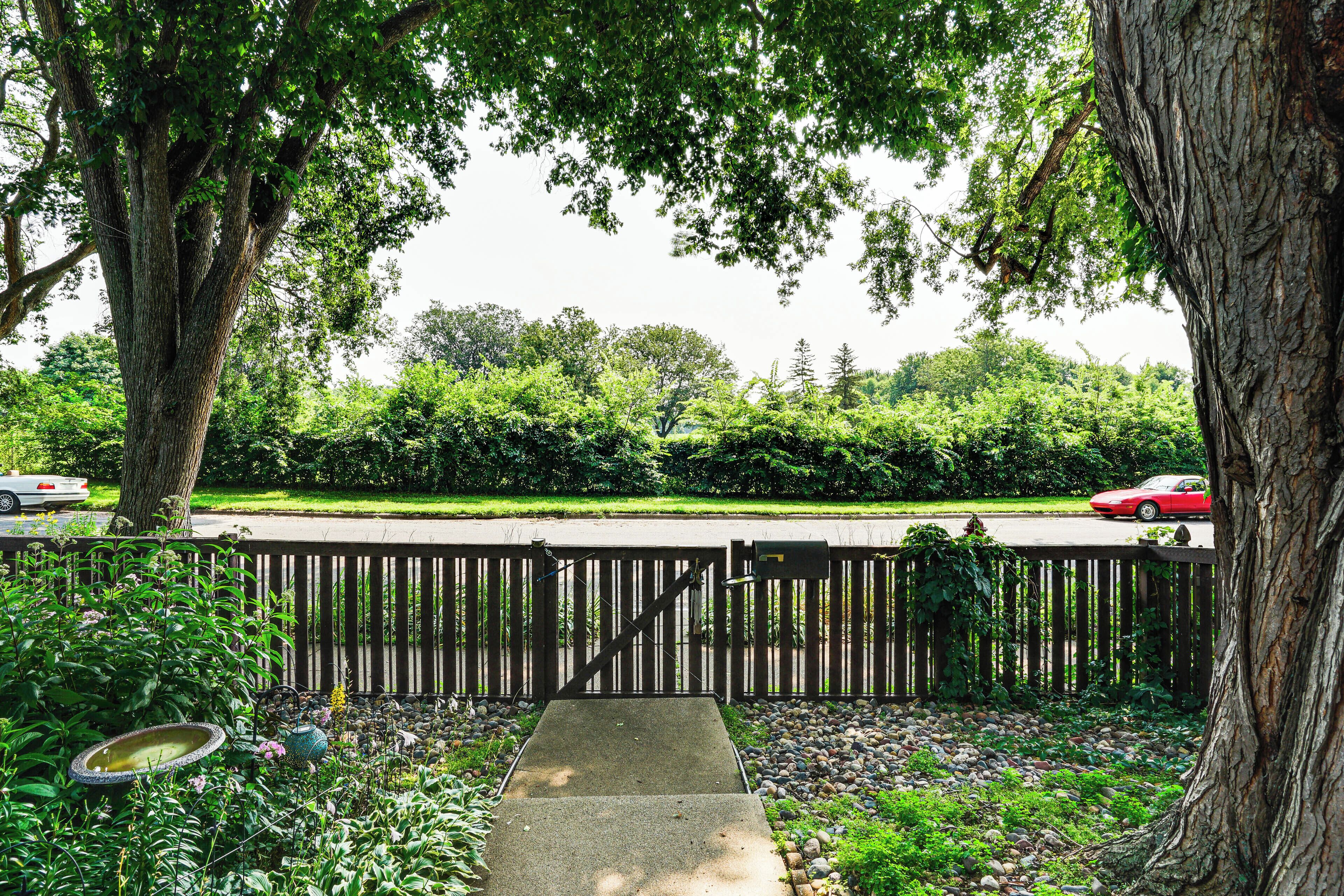 Un jardín trasero cerrado con un camino de hormigón que conduce a una valla de madera.