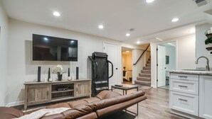 A modern living room with a leather sofa, a flat-screen TV, and a wooden entertainment unit. - Chic Minneapolis Apt - 6 Blocks to Lake Nokomis! (Minneapolis)