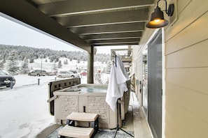A hot tub on a covered porch with a view of a snowy landscape.