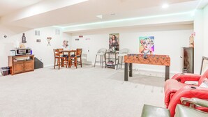 A spacious living room with a dining area, a foosball table, and a red sofa. - Spacious Ewing Township Home: Home Gym & Deck! (Trenton)