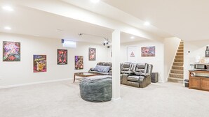 A spacious living room with a large bean bag, leather recliners, a coffee table, and a staircase leading to an upper level. - Spacious Ewing Township Home: Home Gym & Deck! (Trenton)