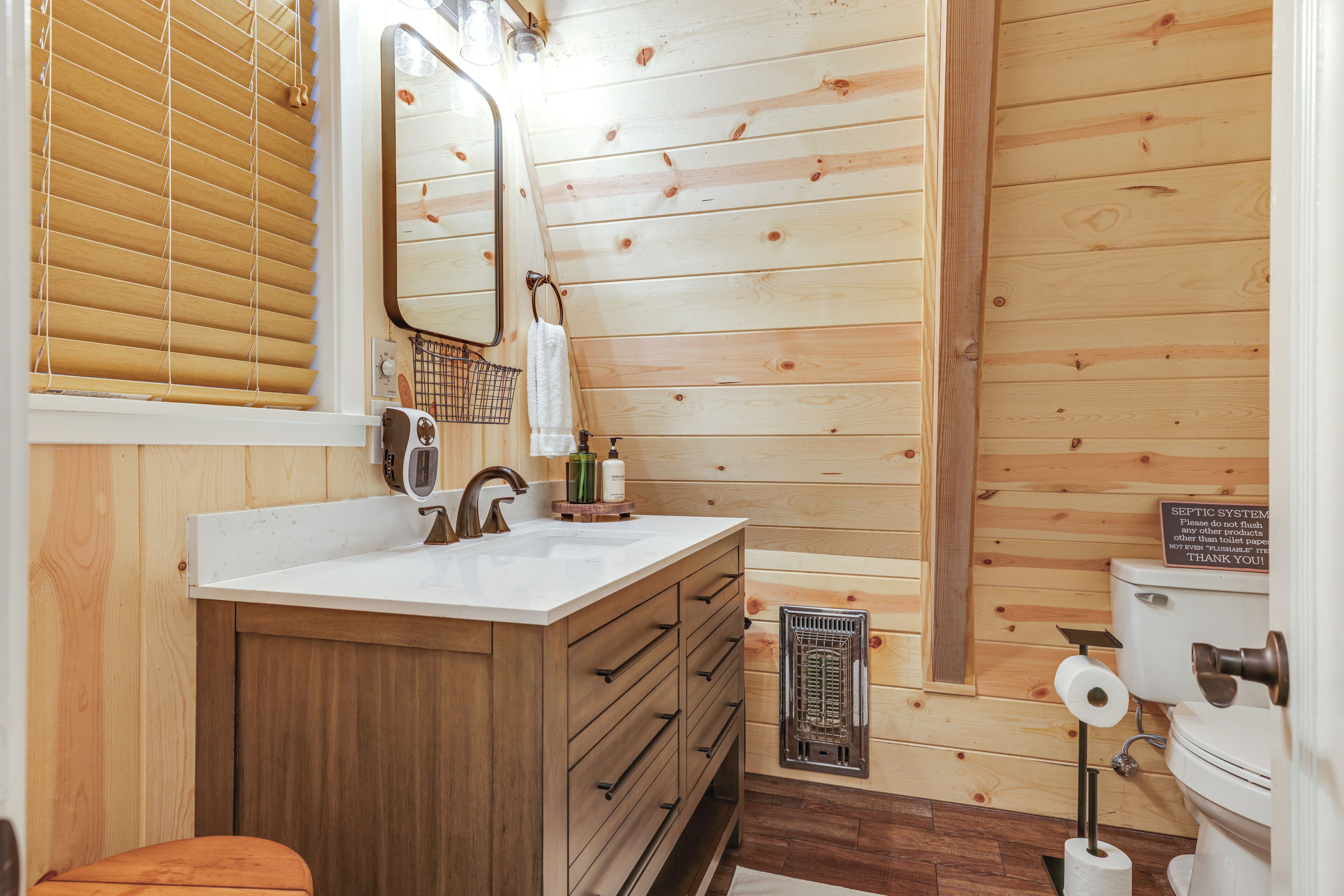 A wooden-paneled bathroom with a sink, mirror, and toilet.