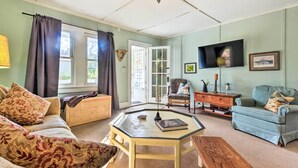 A cozy living room with a sofa, armchair, coffee table, and a television. - Mtn Cottage w/ Fire Pit in Newland! (Newland)