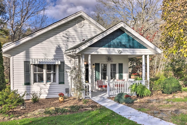 A two-story house with a porch, a small garden, and a pathway leading to the front door.