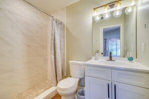 A bathroom with a toilet, a shower, and a vanity with a mirror.