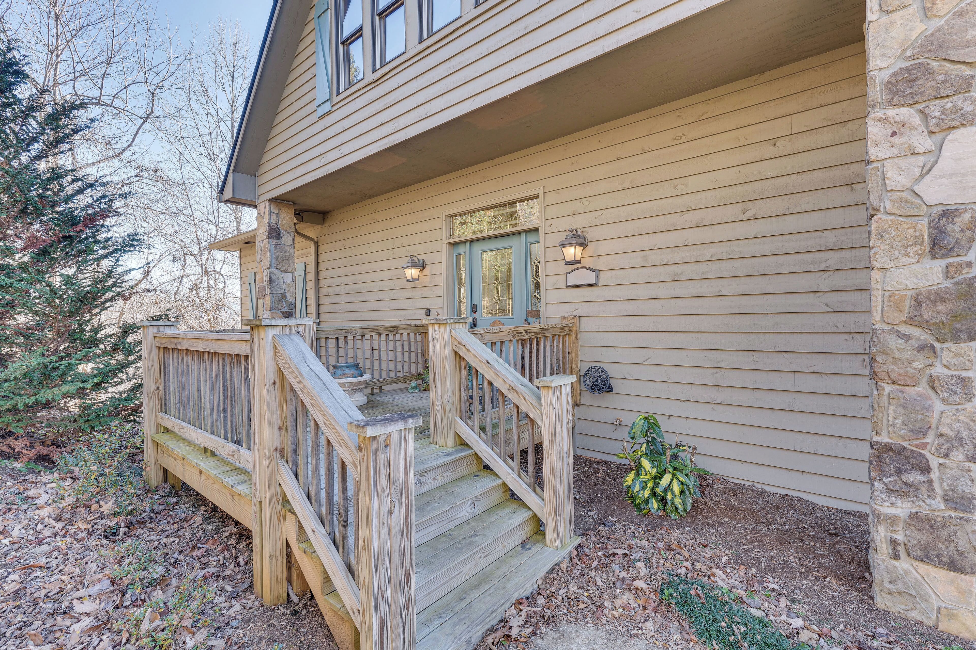 A wooden deck with a stone wall, a wooden staircase, and a door with a window.