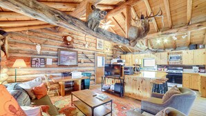 A rustic cabin interior with a wooden ceiling, a dining area, a kitchen with modern appliances, and a living room with a fireplace. - Yellowstone Cabin Getaway Near National Park (Cameron)