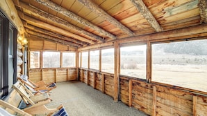 A wooden cabin with a large window, wooden walls, and a carpeted floor. - Yellowstone Cabin Getaway Near National Park (Cameron)