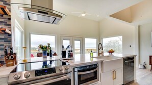 Une cuisine moderne dotée d’un four encastré, d’un lave-vaisselle et d’un grand îlot central avec un plan de travail en verre.