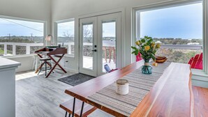 Une cuisine moderne avec un plan de travail en bois, une table à manger et une vue dégagée grâce à de grandes fenêtres.