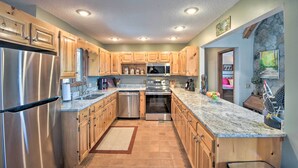 A modern kitchen with stainless steel appliances, wooden cabinets, and granite countertops. - Home w/ Spacious Deck, Bbq, Game Room & Lake Views (Hiawassee)