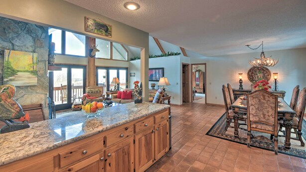 A spacious kitchen with a large island, wooden cabinets, and a dining area with a chandelier. - Home w/ Spacious Deck, Bbq, Game Room & Lake Views (Hiawassee)