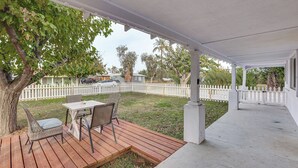 En overdækket terrasse med træterrasse, et bord og stole.