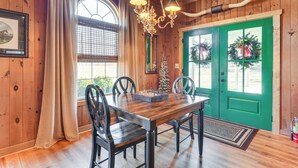 A wooden interior with a dining table, chairs, a chandelier, and a green door with wreaths. - Countryside Cabin Rental ~ 10 Mi to Wadesboro! (Wadesboro)