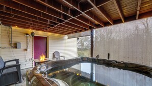 Una vasca idromassaggio con un pontile in legno, una zona fuoco e un'area coperta con sedie e una lanterna.