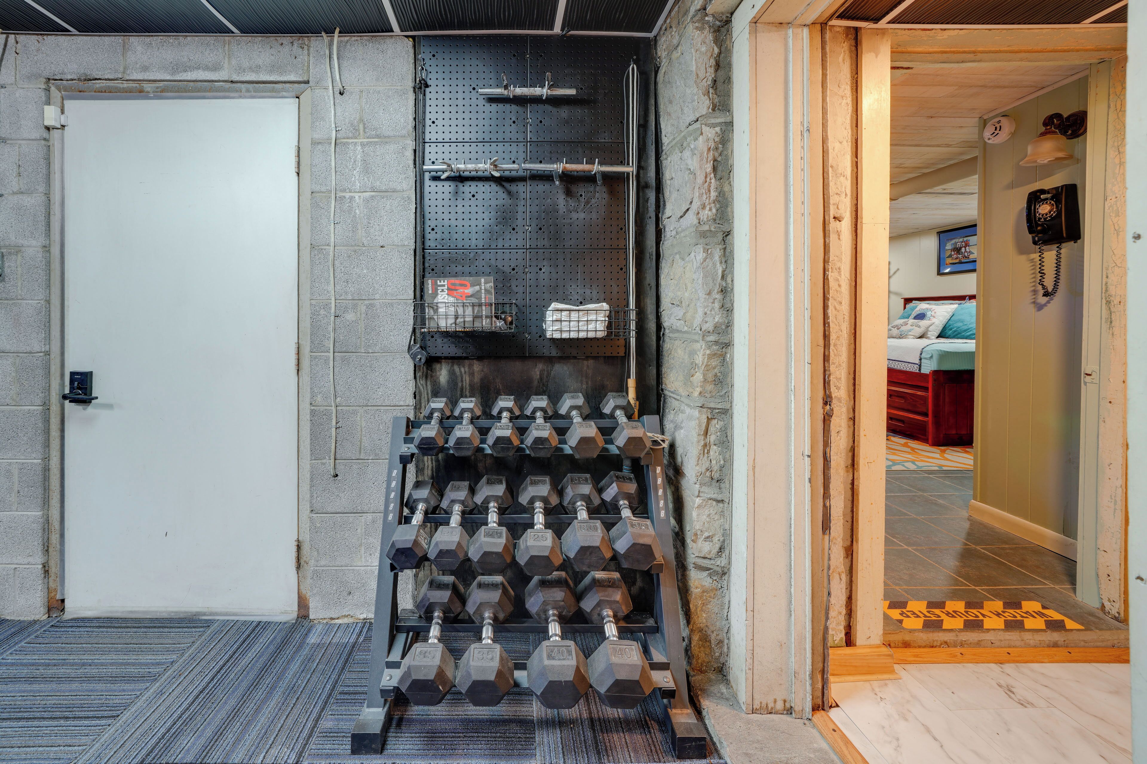 A gym with a wall-mounted dumbbell rack and a door leading to another room.