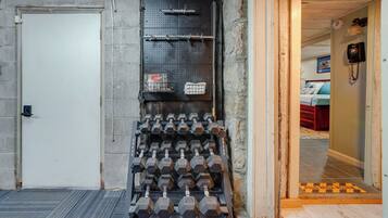 A gym with a wall-mounted dumbbell rack and a door leading to another room.