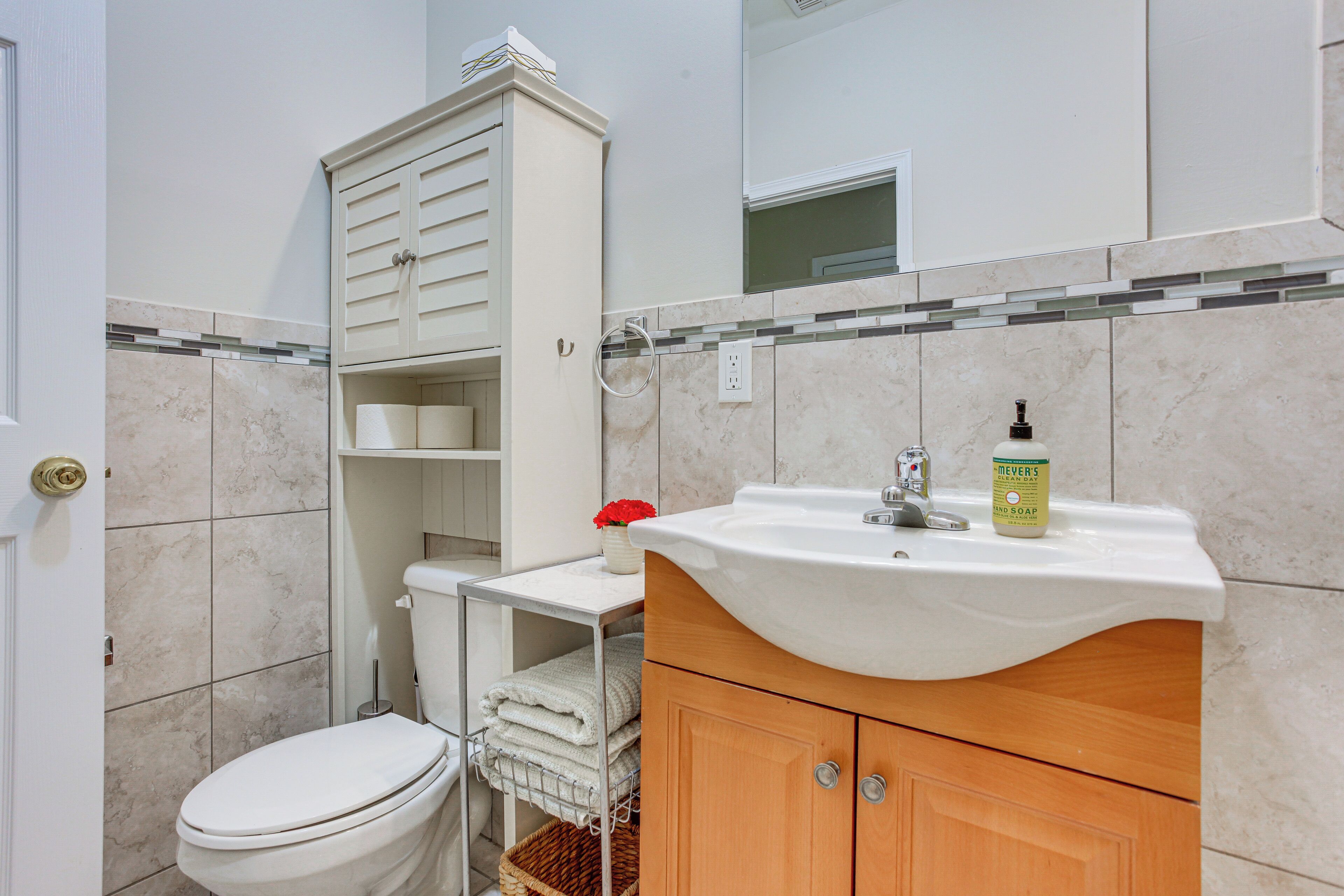 Une salle de bain comprenant des toilettes, un lavabo, un meuble et un miroir.