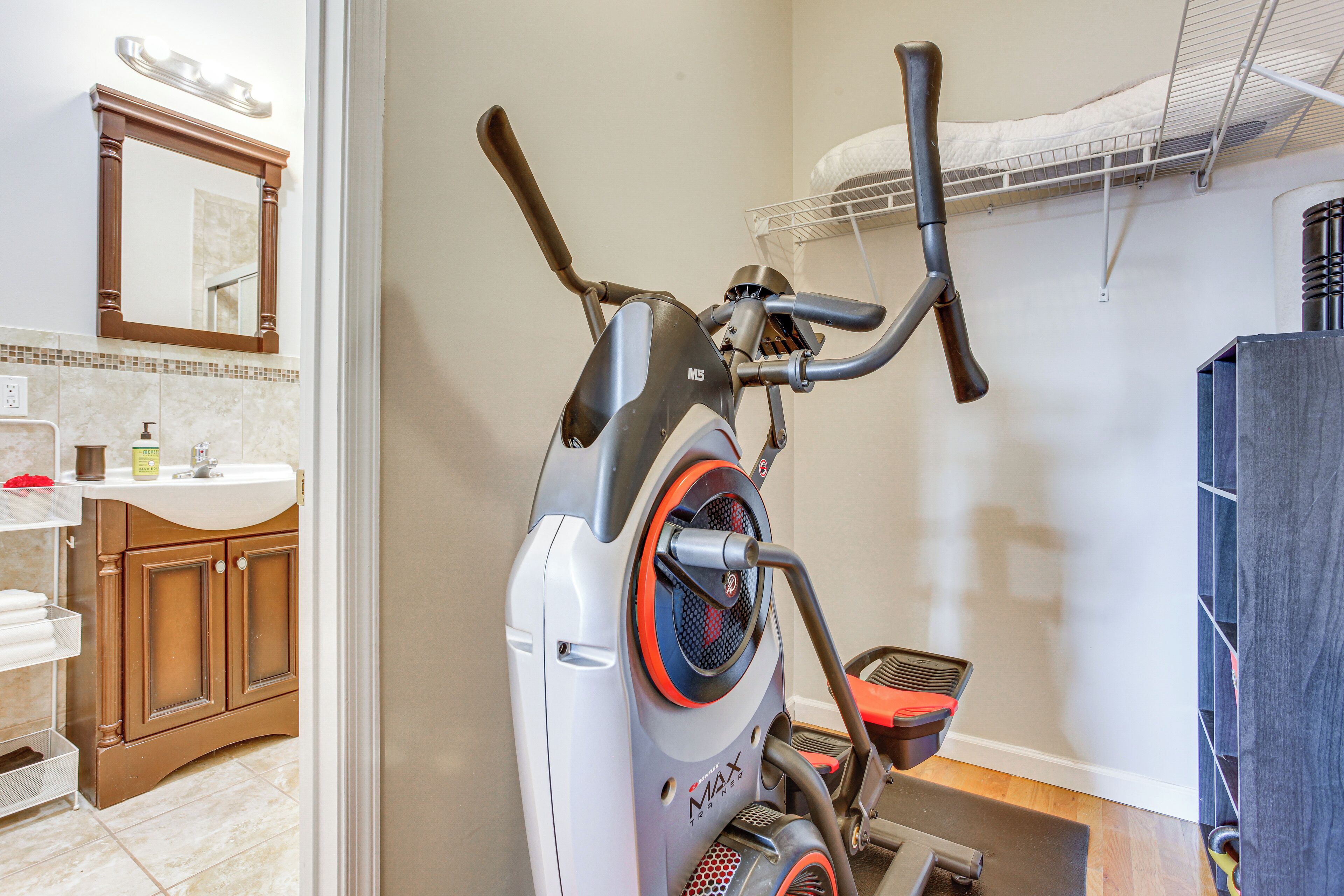 A stationary exercise bike in a bathroom with a sink, mirror, and towel rack.