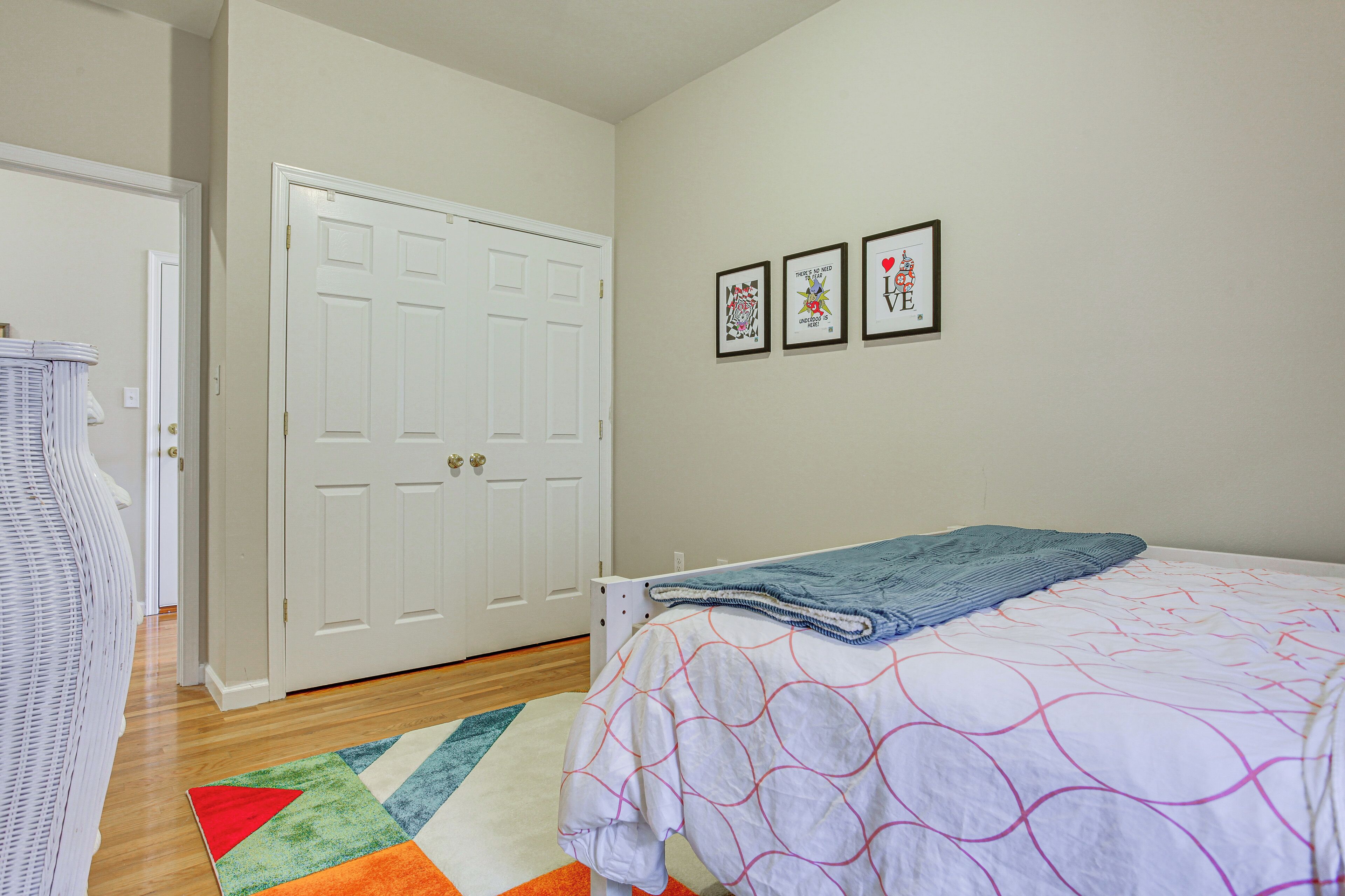 A bedroom with a bed, a door, and three framed pictures on the wall.