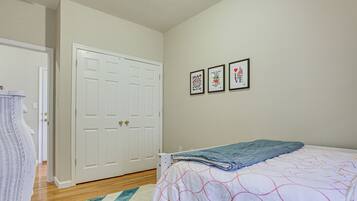 A bedroom with a bed, a door, and three framed pictures on the wall.