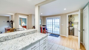 A spacious kitchen with a marble countertop, a dining area with a table and chairs, and a view through a glass door to the outside. - East Wenatchee Home ~ 2 Mi to Columbia River! (East Wenatchee)