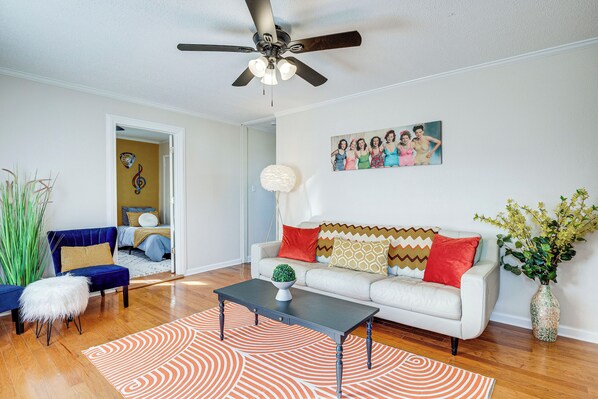 A living room with a white sofa, a blue chair, a coffee table, a ceiling fan, and a painting on the wall. - Winchester Home w/ Views Near Tims Ford Lake! (Winchester)