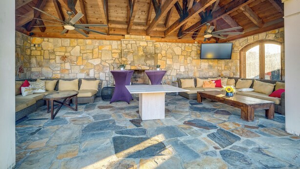 An outdoor patio with stone flooring, wooden beams, and seating arrangements including sofas and tables. - Elegant Paris Manor w/ Private Pool! (Paris)