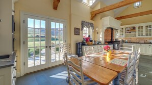 A spacious kitchen with a large island, white cabinetry, and a view of the countryside through a sliding door. - Elegant Paris Manor w/ Private Pool! (Paris)