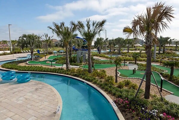 A pool area with a water slide, palm trees, and a mini-golf course. - 4323sl-storey Lake Resort 5 Bedroom Townhouse by RedAwning (Kissimmee)