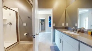 A modern bathroom with a large mirror, a sink, and a toilet. - 4323sl-storey Lake Resort 5 Bedroom Townhouse by RedAwning (Kissimmee)