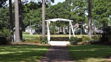 A gazebo with a brick pathway leading to it, surrounded by trees and a well-maintained lawn.