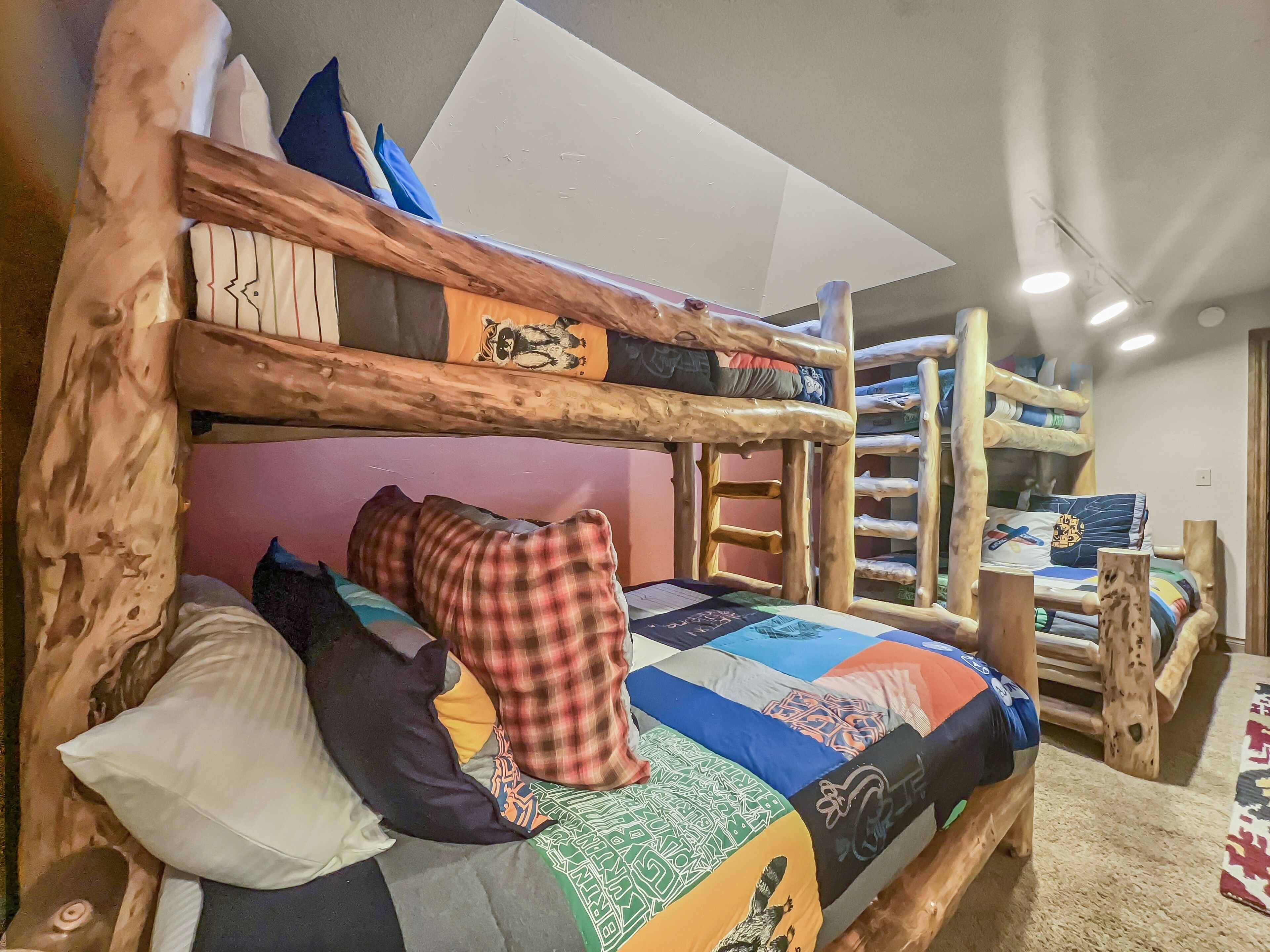 A bunk bed with a wooden frame, multiple pillows, and a colorful quilt.