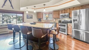 A modern kitchen with a large island, bar stools, stainless steel appliances, and a view of a snowy landscape. - Be410 Bridge End Pet Friendly 3 Bedroom Condo by RedAwning (Copper Mountain)