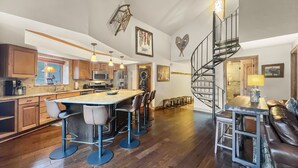 A spacious kitchen with modern appliances, a central island with bar stools, and a spiral staircase leading to an upper level. - Be410 Bridge End Pet Friendly 3 Bedroom Condo by RedAwning (Copper Mountain)