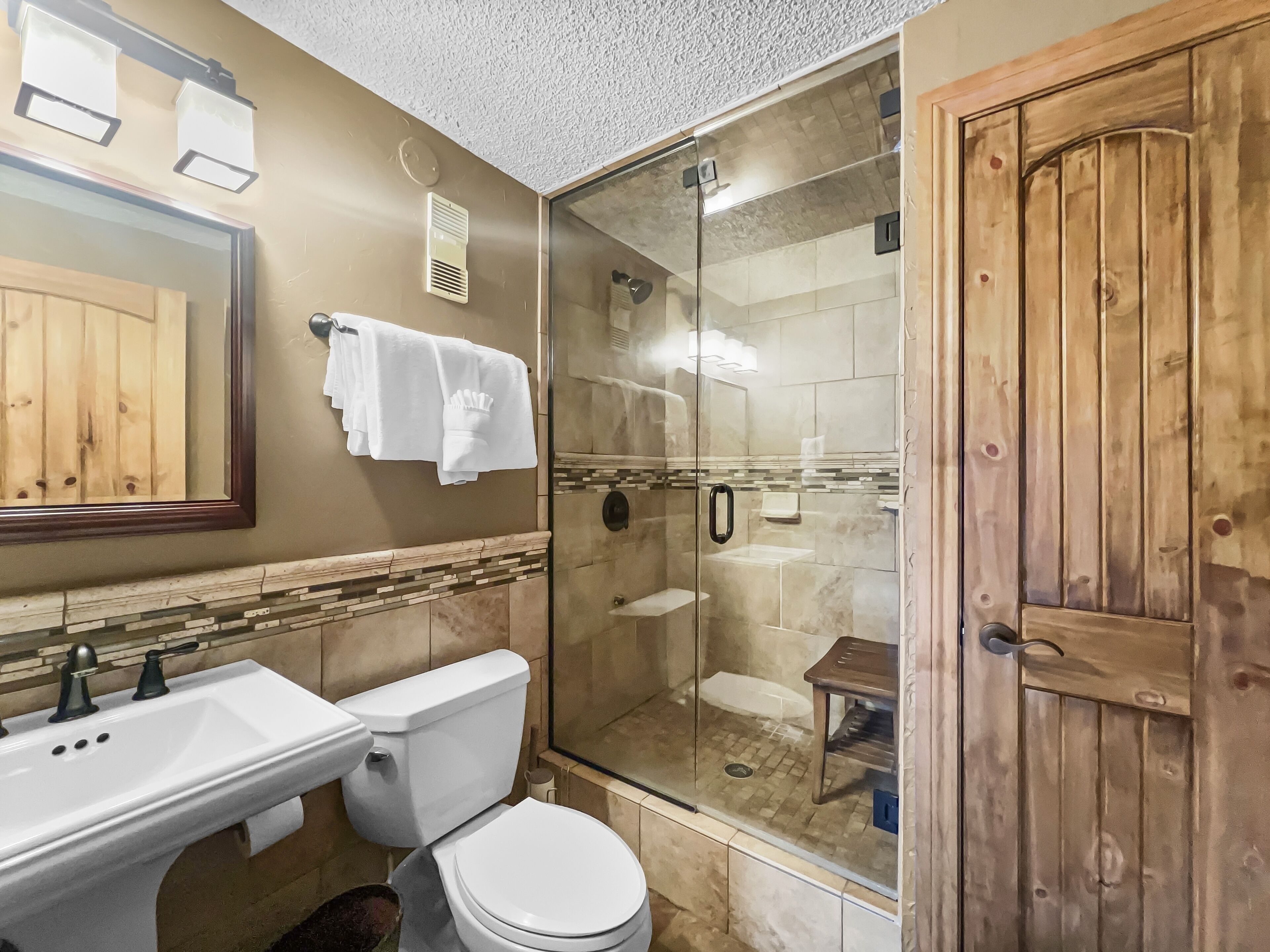 A bathroom with a sink, toilet, and glass-enclosed shower.