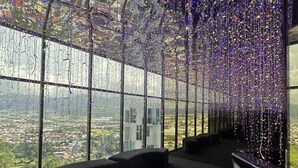 Een modern interieur met een panoramisch uitzicht door grote ramen, een zithoek met een gebogen bank en een plafond versierd met hangende lampen.