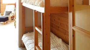 Ein Schlafraum mit Etagenbetten, Holzwänden und einer Deckenleuchte.