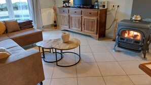 Una sala de estar con un sofá, una mesa de centro, un televisor, un armario y una estufa de leña.