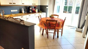 Una cocina con una isla central, una mesa de comedor con sillas y vistas al exterior a través de un ventanal.
