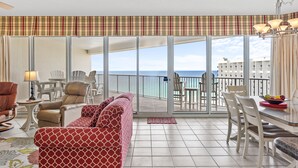 Una habitación de hotel con balcón, zona de comedor y sofá.