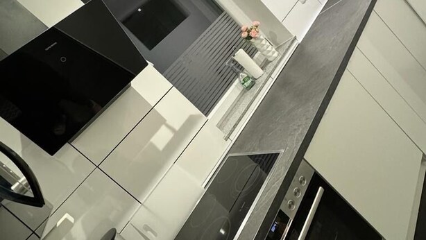 Una cocina moderna con horno empotrado, cafetera y lavabo.
