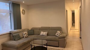 Una sala de estar moderna con un sofá modular, una mesa de centro de vidrio y un ventanal amplio.