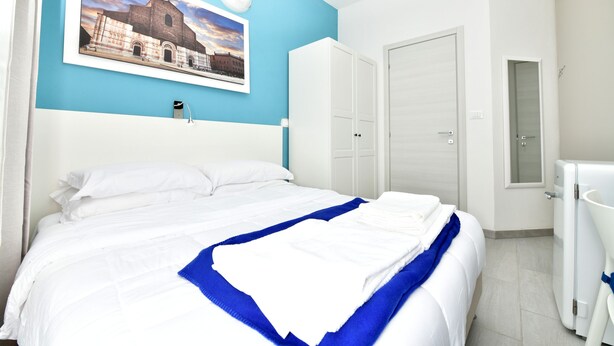 Een hotelkamer met een bed, een kledingkast, een badkamer en een aan de muur bevestigd schilderij.