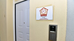 Een deur met een intercom aan de muur en een bord waarop 'A San Lazaro Rooms' staat, inclusief een telefoonnummer.