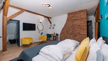 Un dormitorio moderno con una cama, pared de ladrillo, techo de madera, un escritorio pequeño, una silla y un televisor.