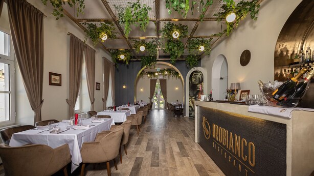 A restaurant interior with tables set for dining, a bar area, and a view through an archway. - Haller Boutique (Targu Mures)